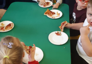Dzieci w trakcie jedzenia pizzy.